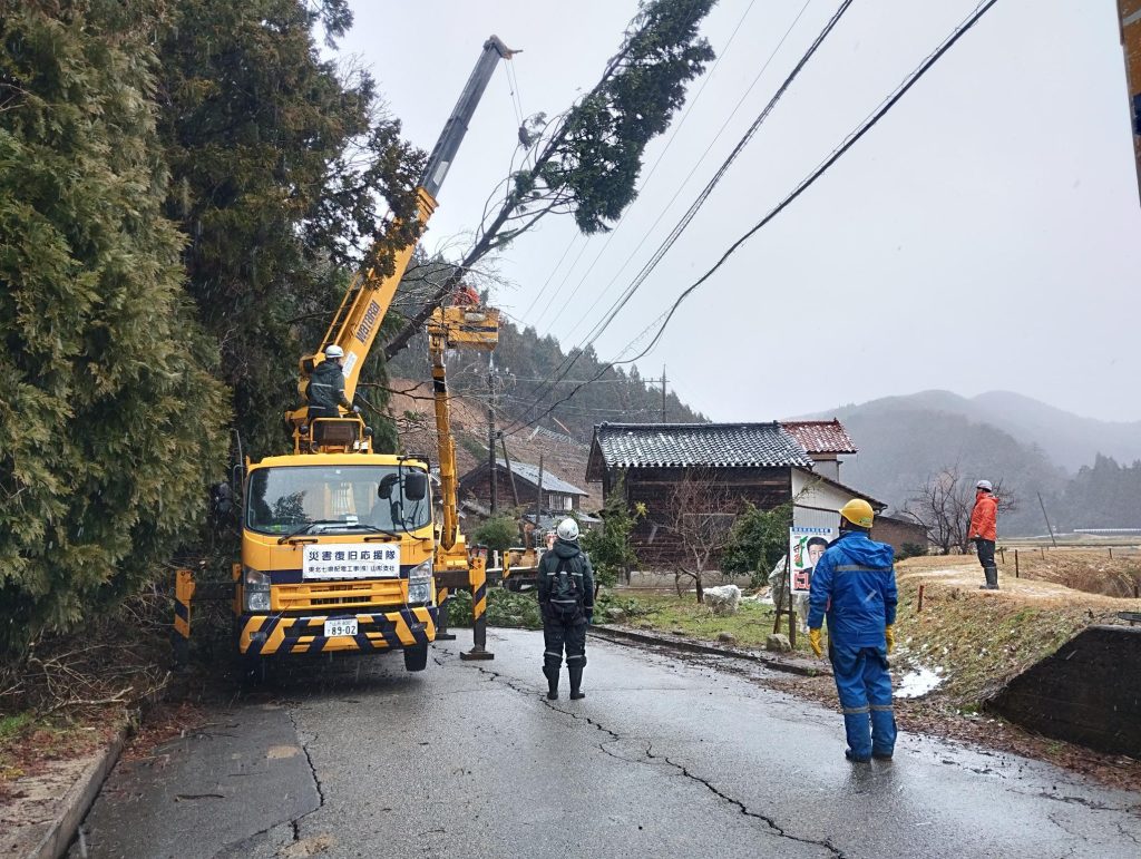 道路上の倒木をクレーンで釣り上げている。作業員数名がが安全確認している。