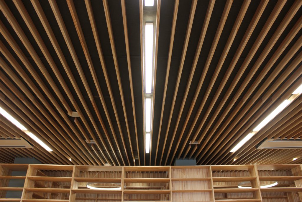 メディアセンターの照明。天井が木製のルーバーになっている。ルーバーの間に照明を収めている。