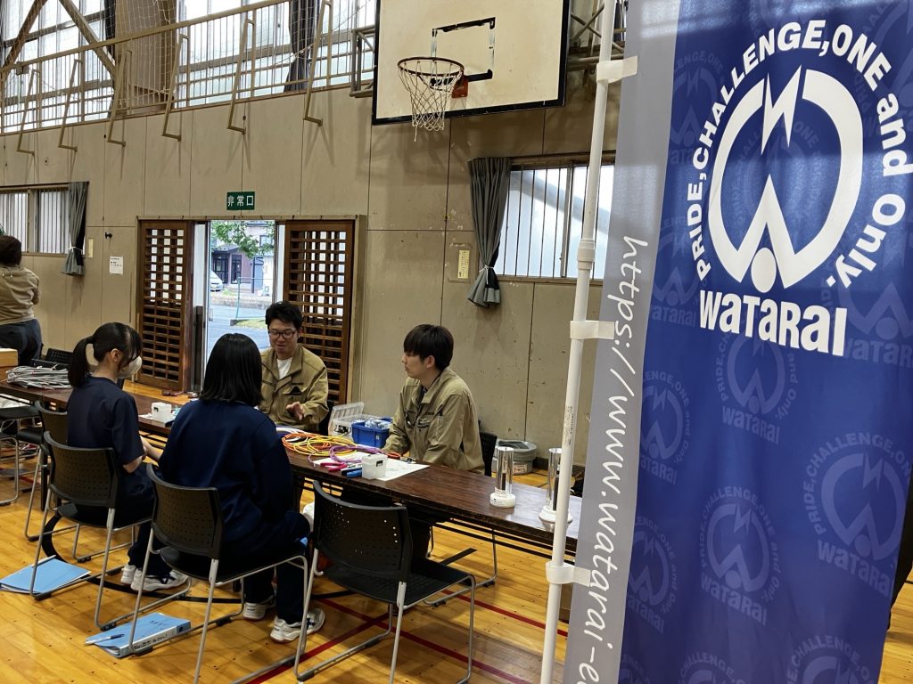当社の男性社員2名が女子生徒2名に説明している