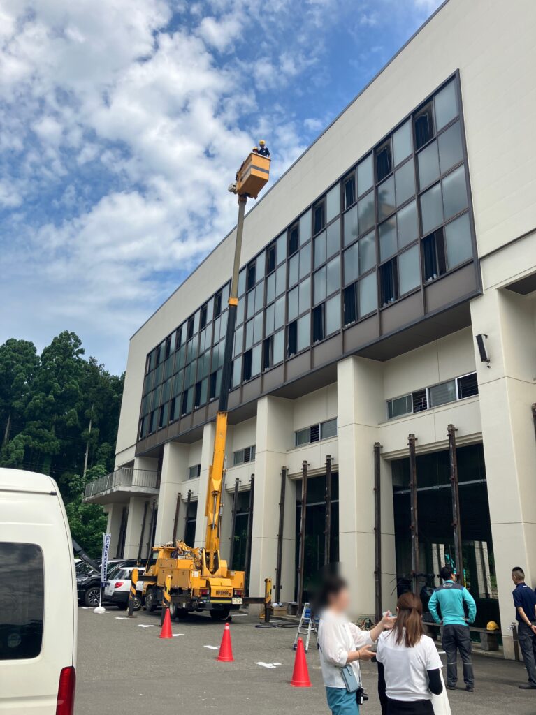 高所作業車のバケットに生徒2名と弊社社員１名が乗っている