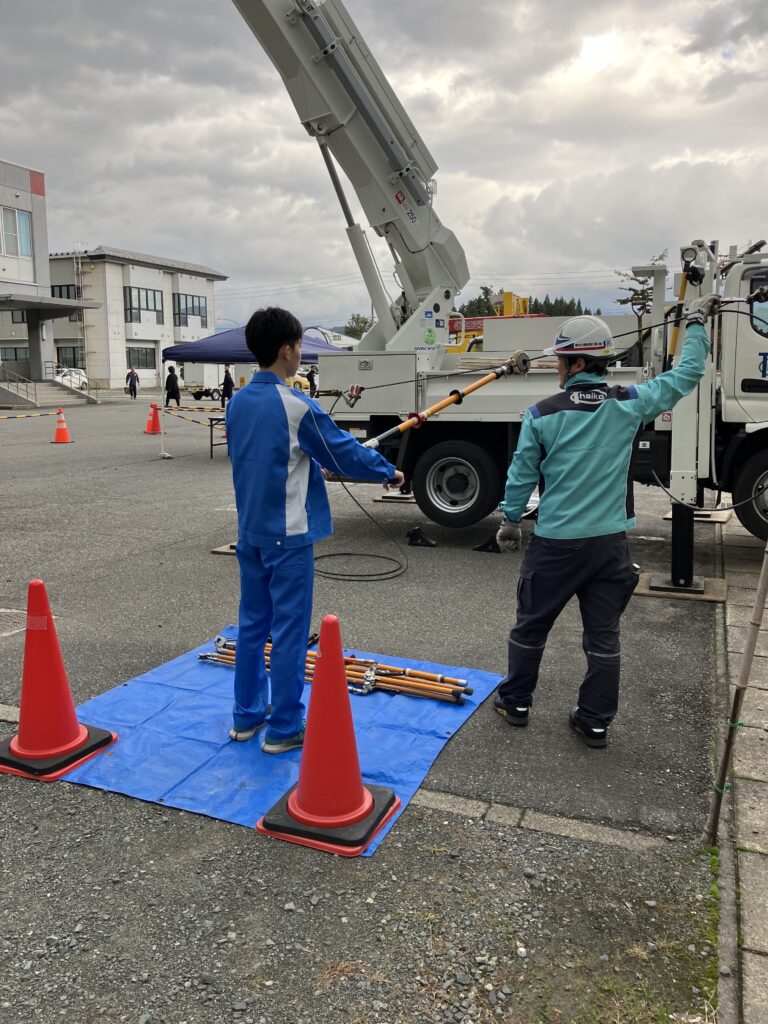 室外で配電線の皮むき体験中の様子