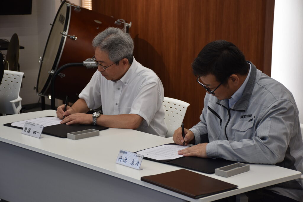 田川地区吹奏楽連盟様と当社代表取締役がサインを交わしている様子